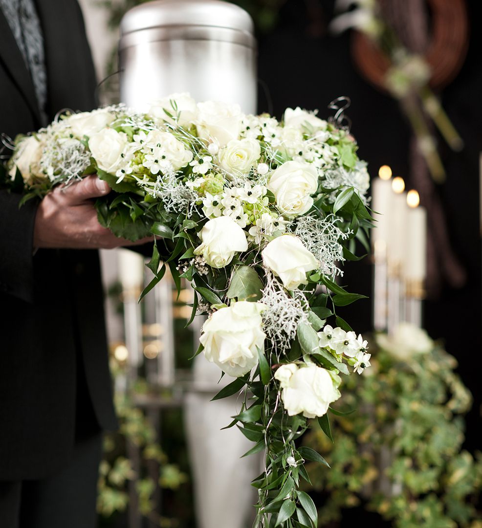 Ein Blumengebinde vor einer Stahlurne.